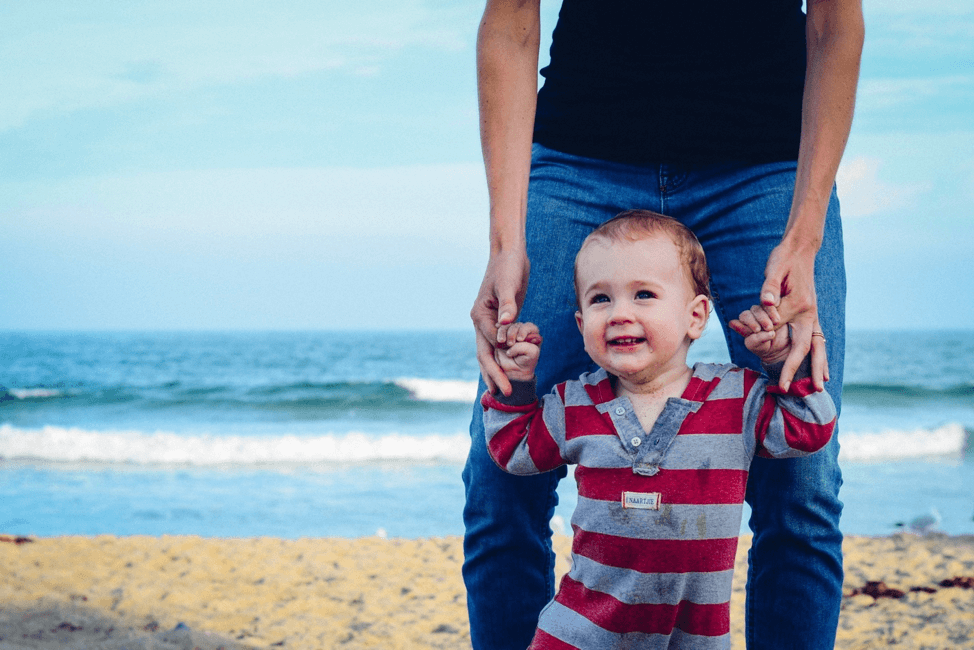 father helping young son walk at the beach