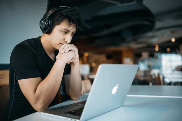 photo of a man on his laptop wearing headphones