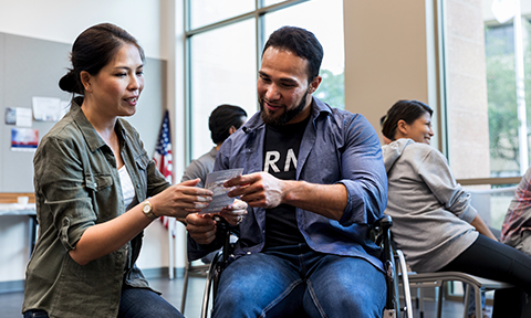 A Veteran in a wheelchair getting an informative pamphlet from a woman