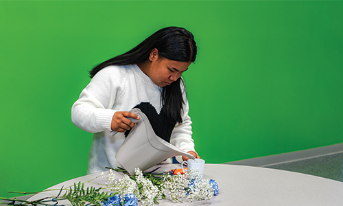 TSC student watering a new floral arrangement