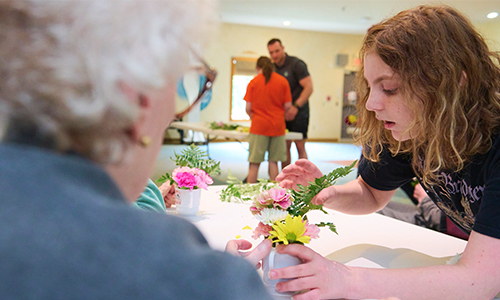 TSC student helping a resident at an assistant living facility create a floral arrangement