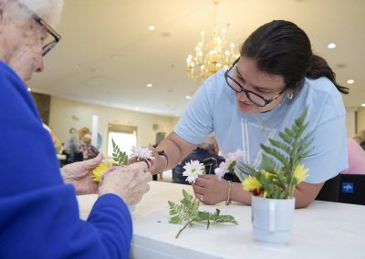 A TSC student helping an assisted living resident create a floral arrangement