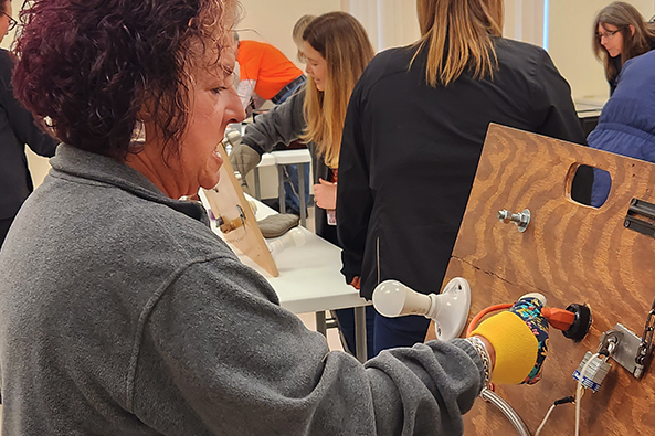 A woman at the Project ABLE mobile dexterity challenges simulation station
